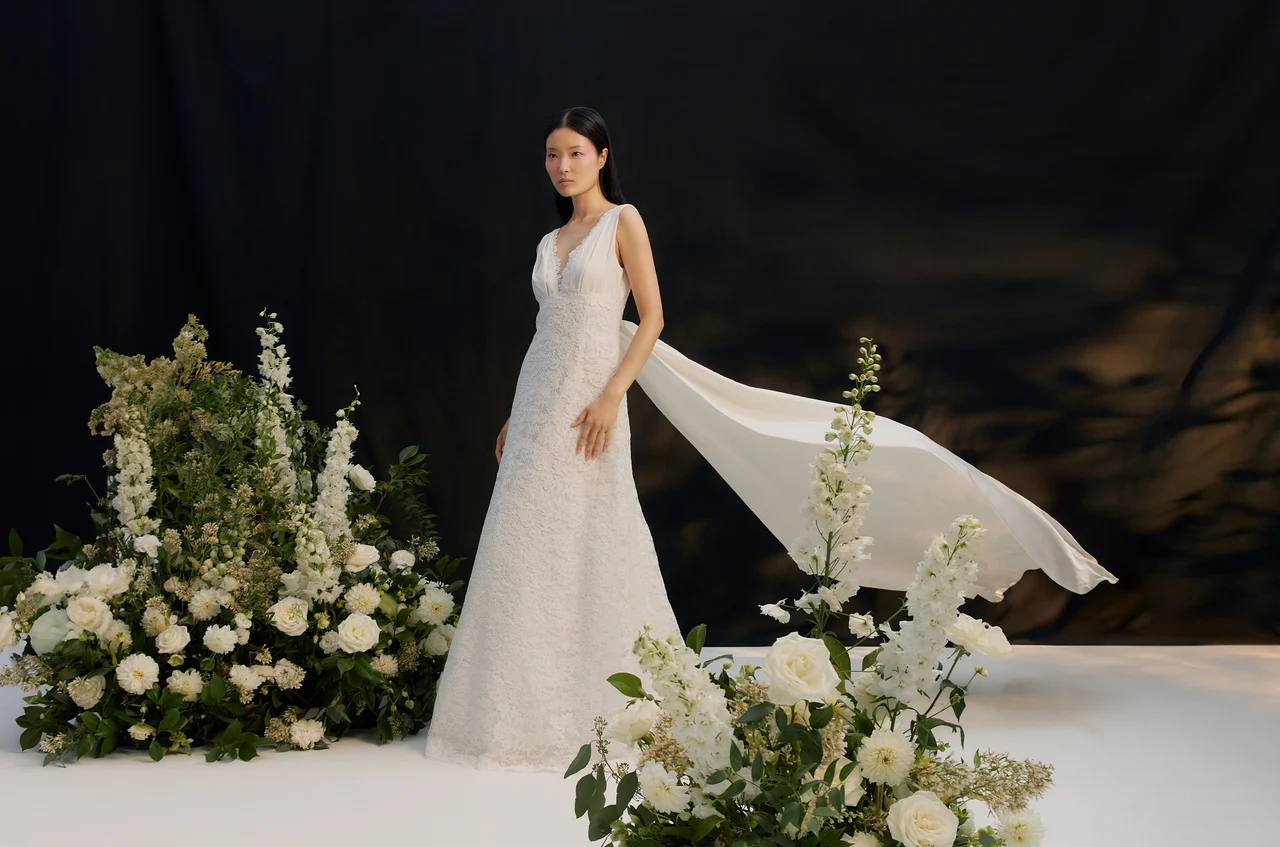 Bride and floral arrangements against a dark studio backdrop