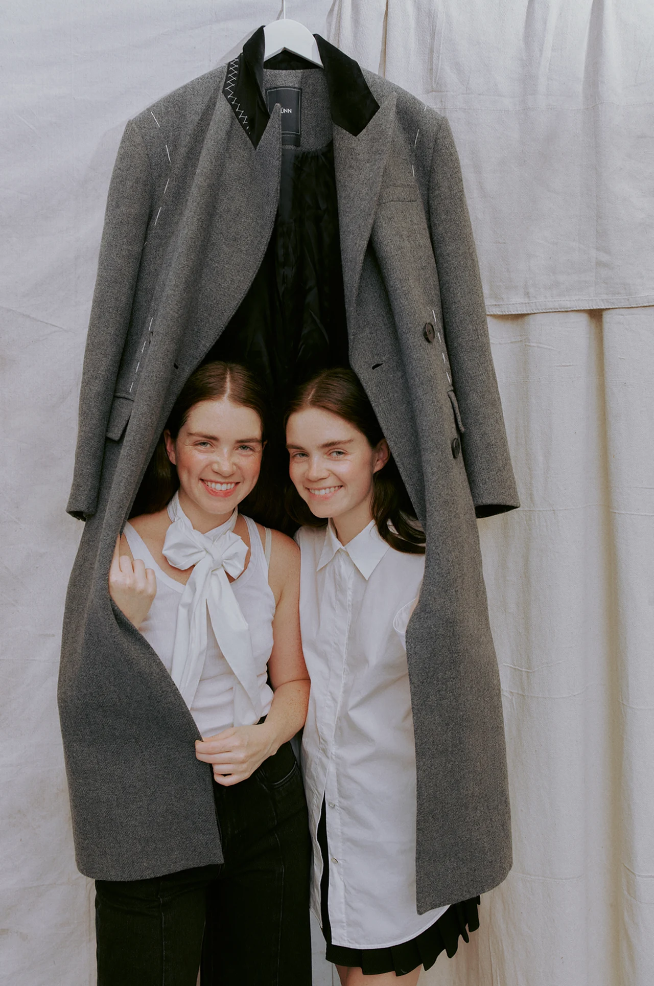 Two models beneath an oversized tailored jacket