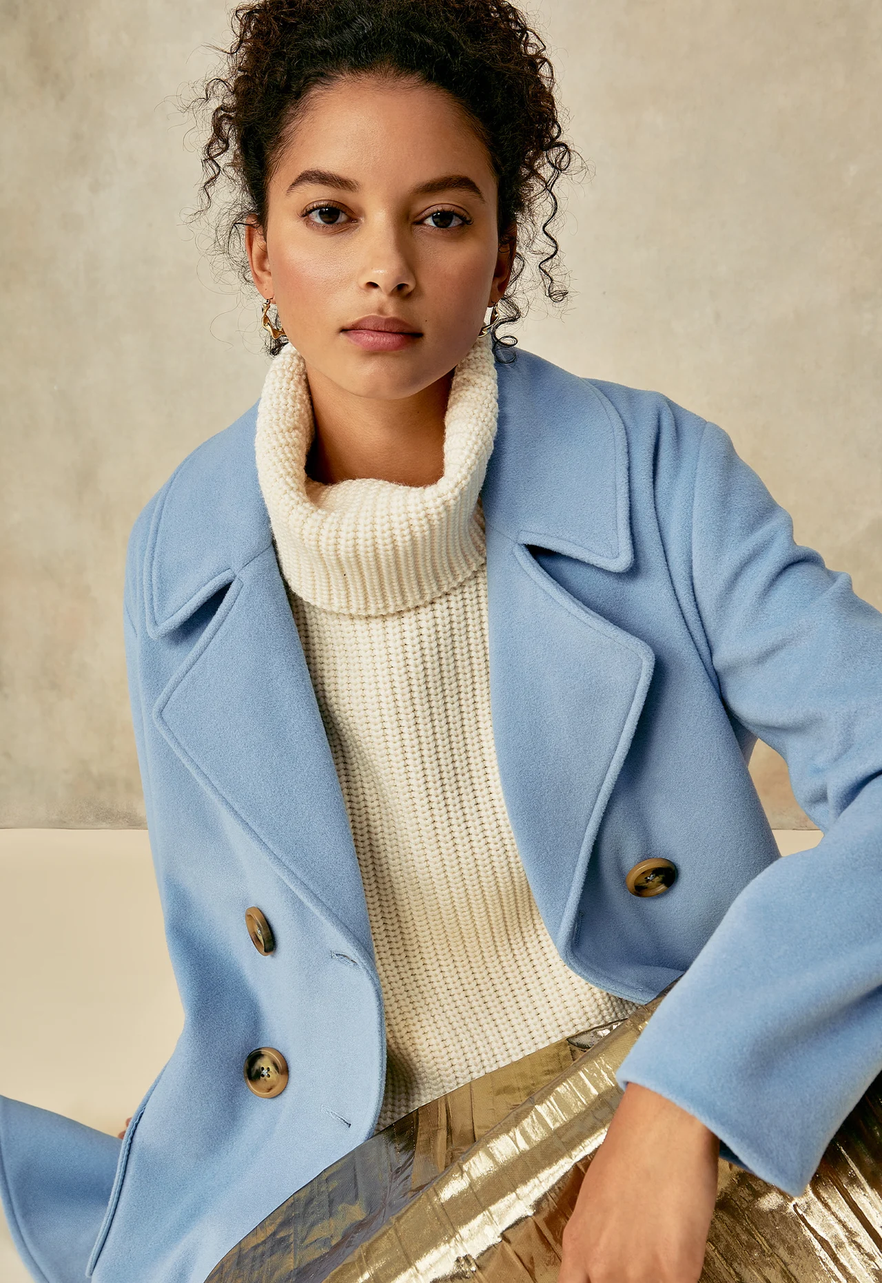 Model wearing a blue coat and cream knitwear