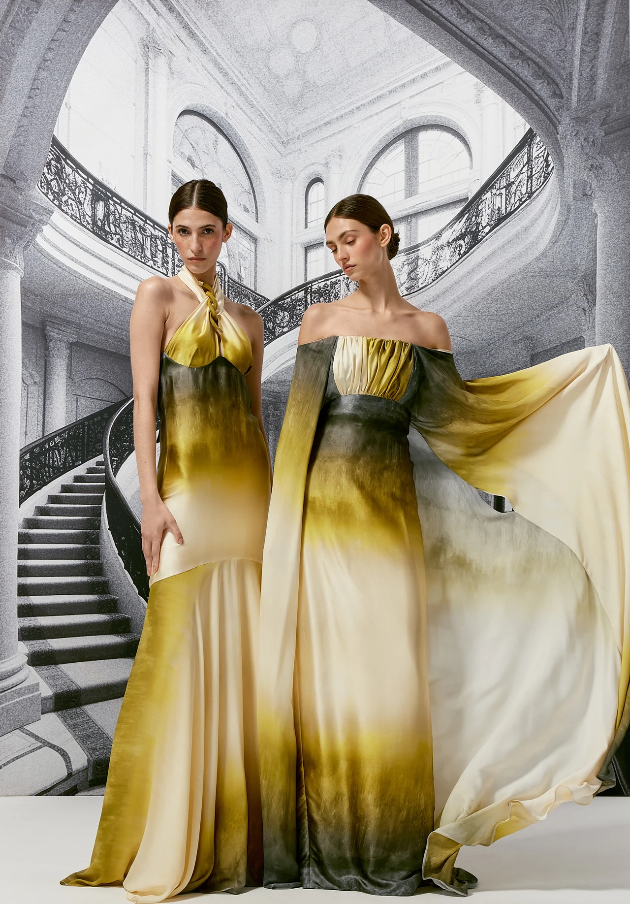 Two models in flowing gold and green gowns